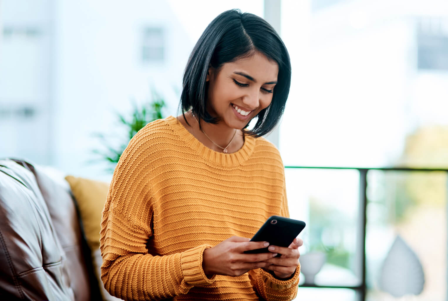 Woman in yellow sweater using phone